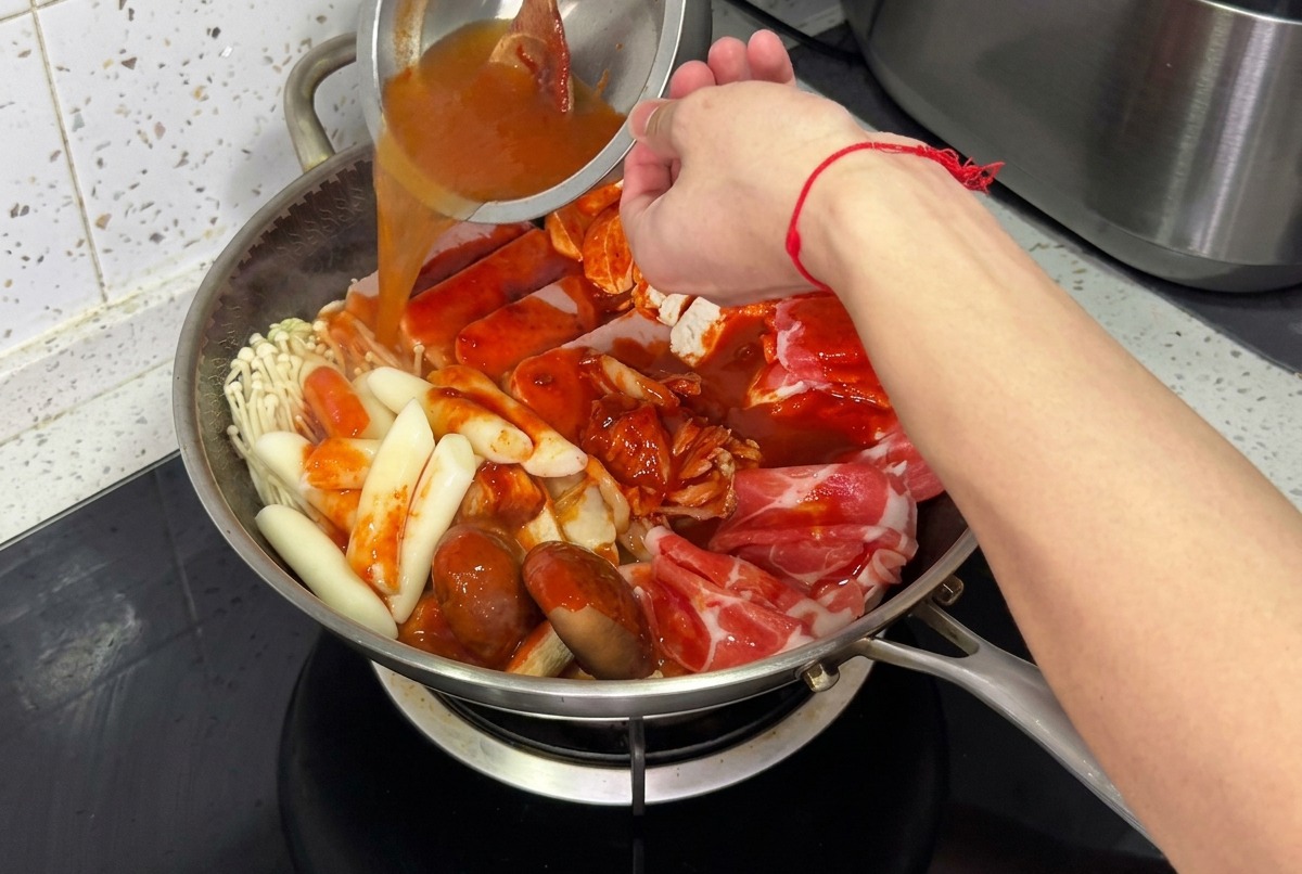 The stew pot being filled with water and covered with a glass lid, ready for simmering.