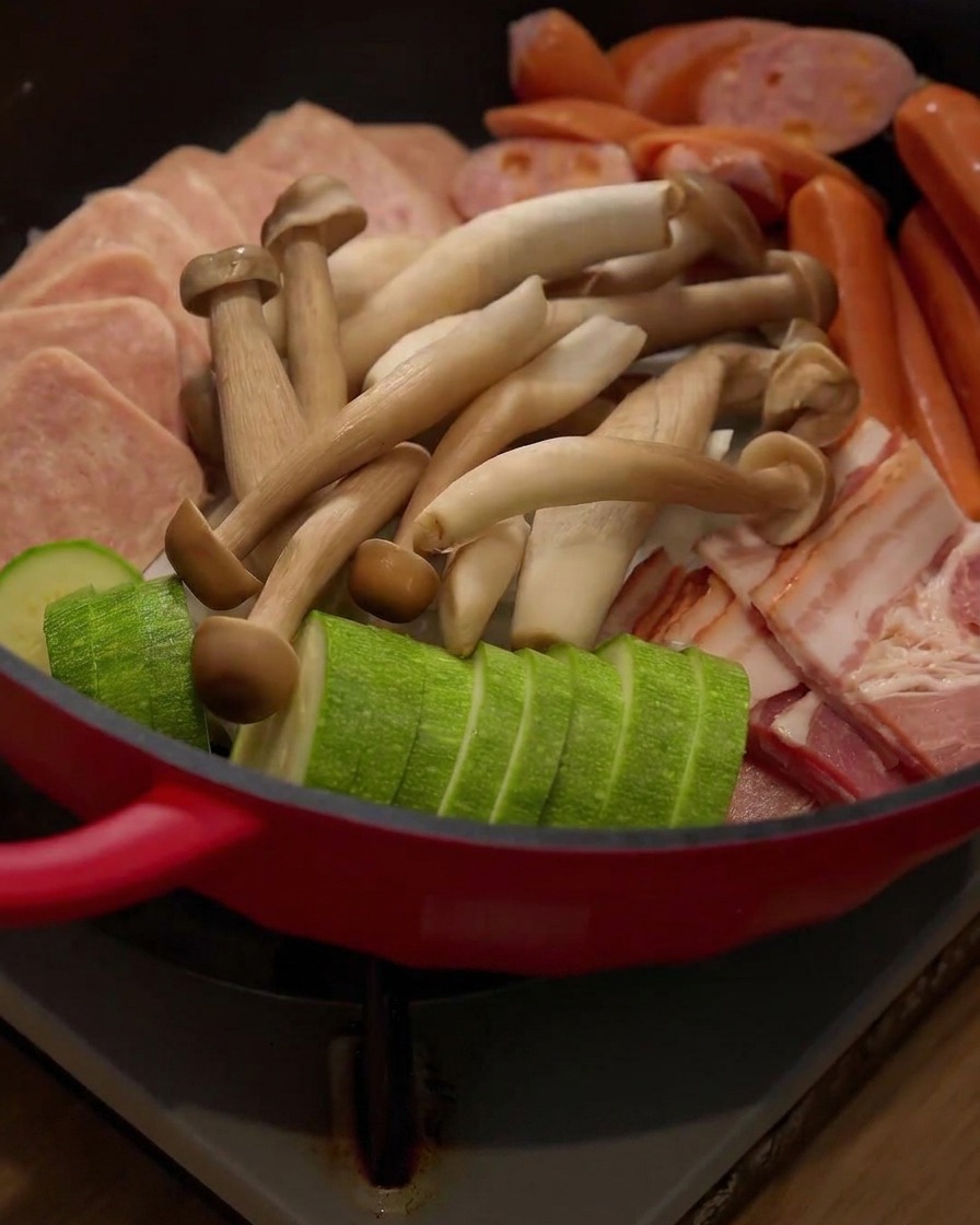 Fresh enoki mushrooms being added into the hot pot arrangement.
