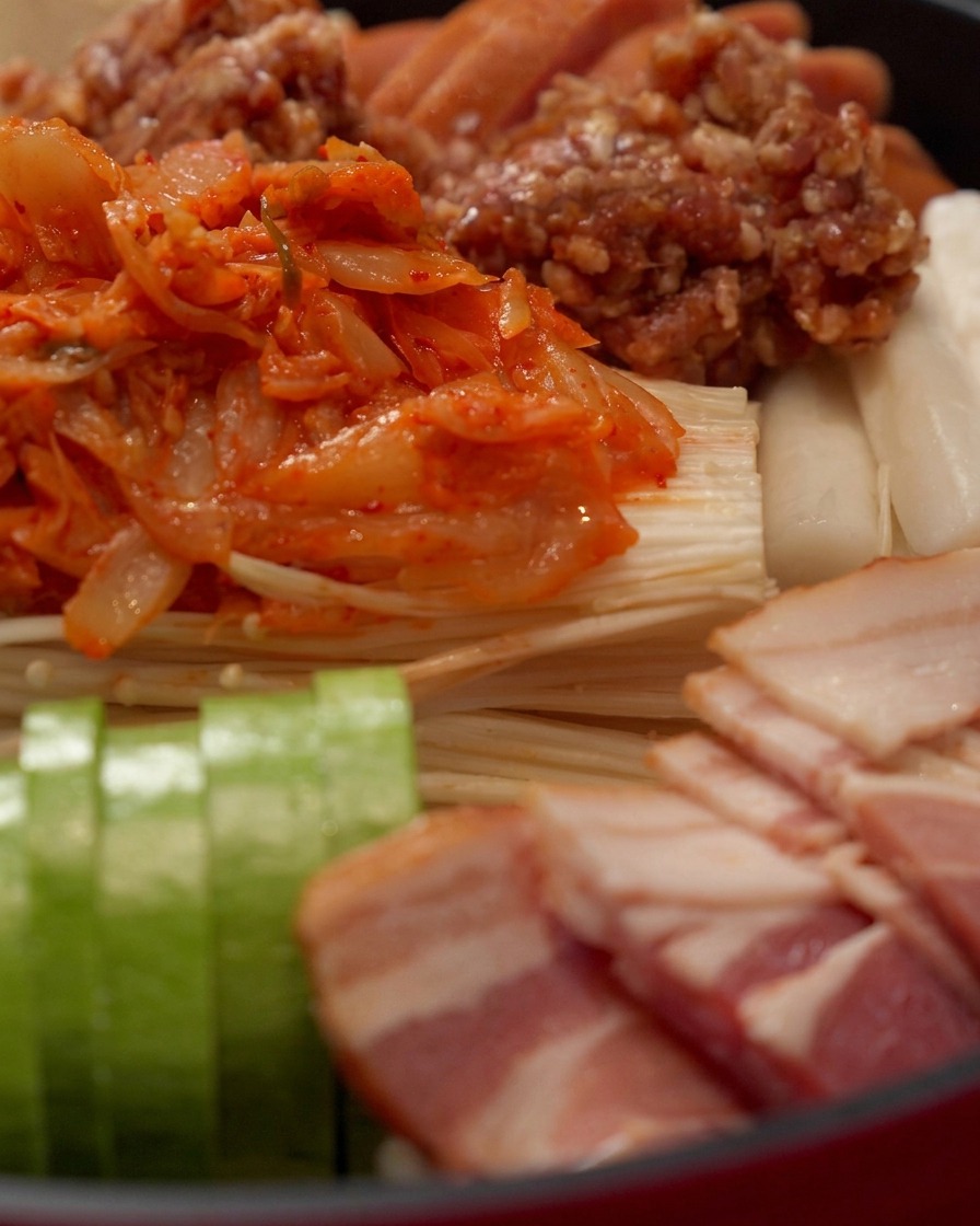 Spicy red hot pot sauce being poured across the top of the arranged ingredients.