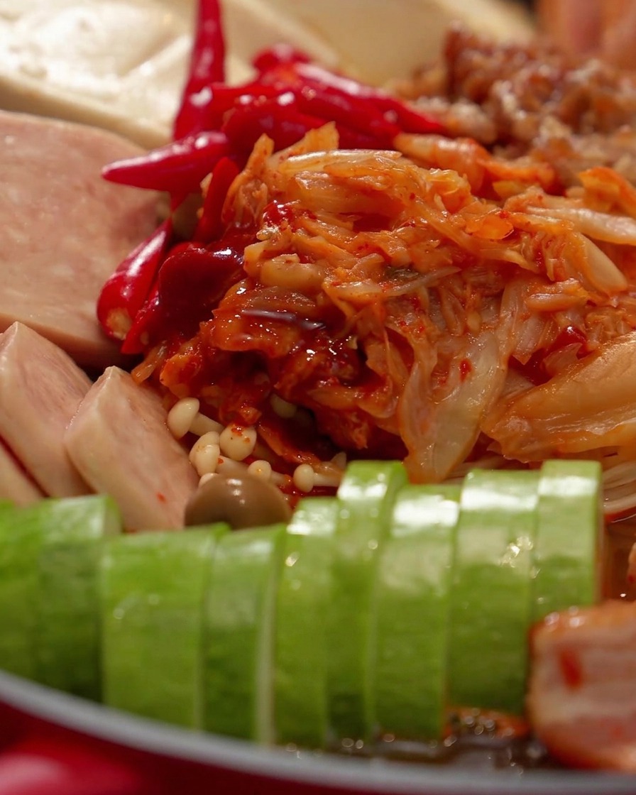 A close-up view of a glass lid covering the ingredients inside the red hot pot.