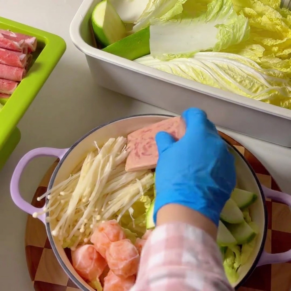 Luncheon meat slices being arranged inside the cooking pot.
