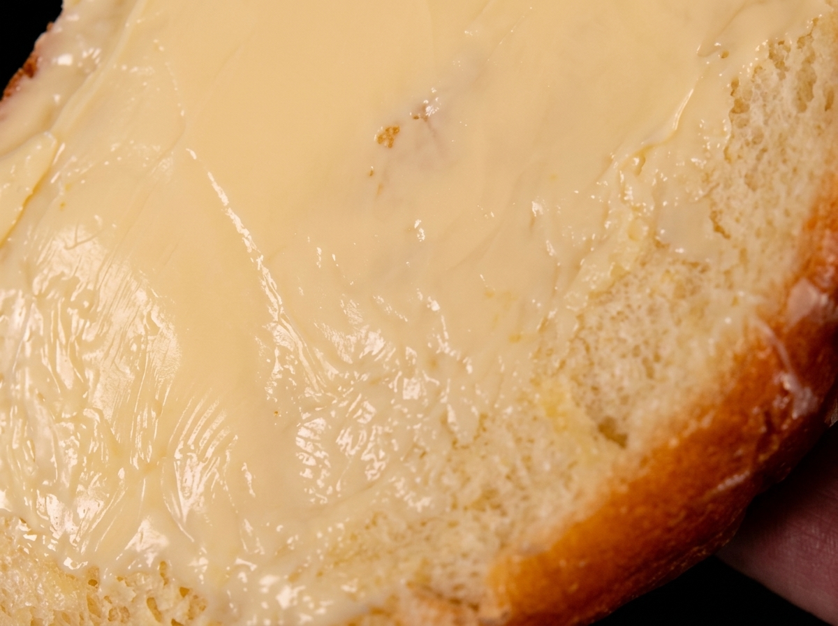 A single slice of bread coated with butter, resting butter-side down in a hot pan.