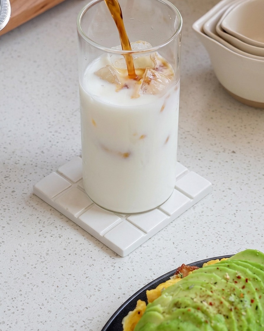 Fresh espresso being poured into a glass of iced milk, creating a swirling gradient pattern.