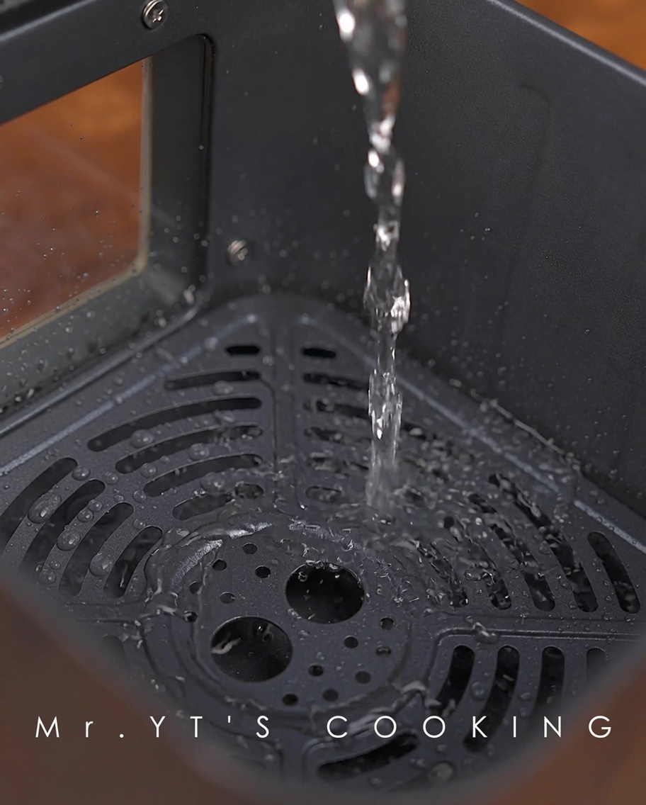 Water being poured into the bottom of the air fryer basket.