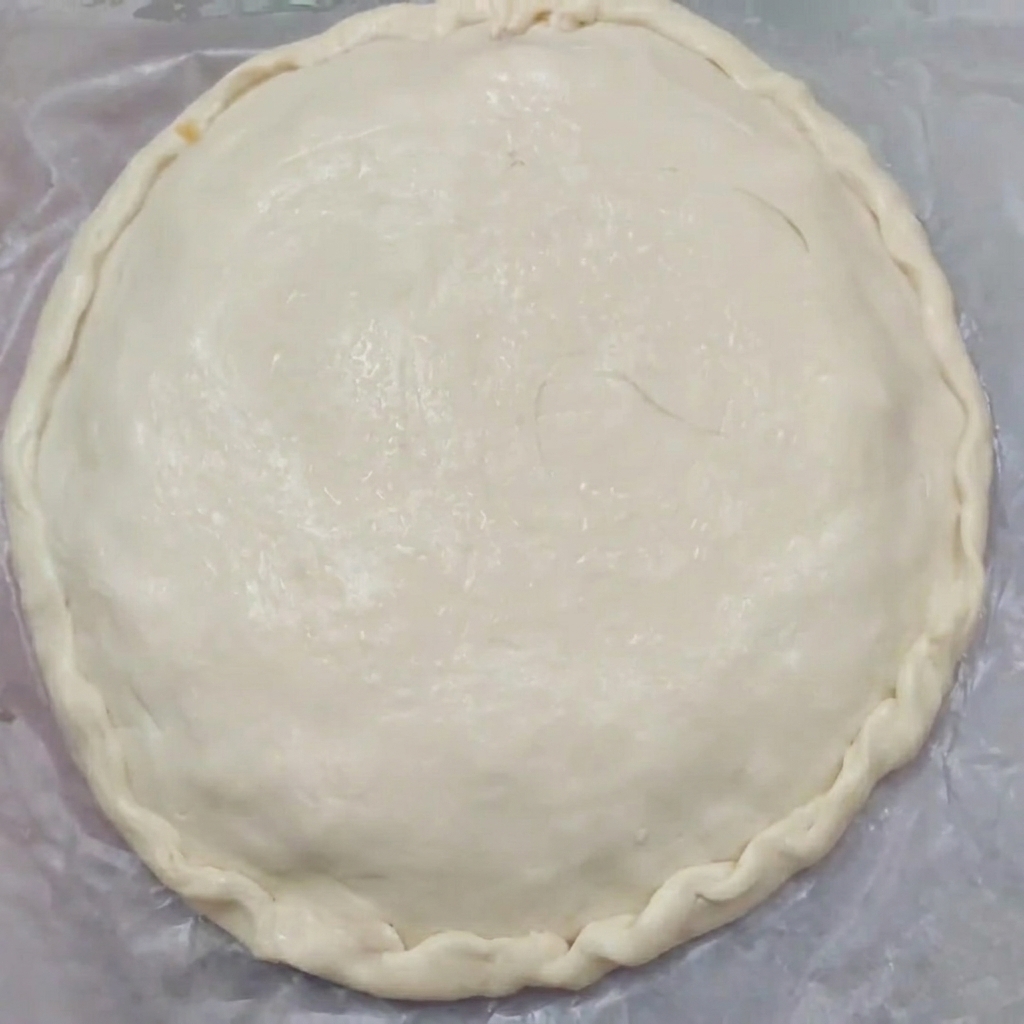 Close-up of a raw pie with beautifully crimped edges sealing the top and bottom pastries together.