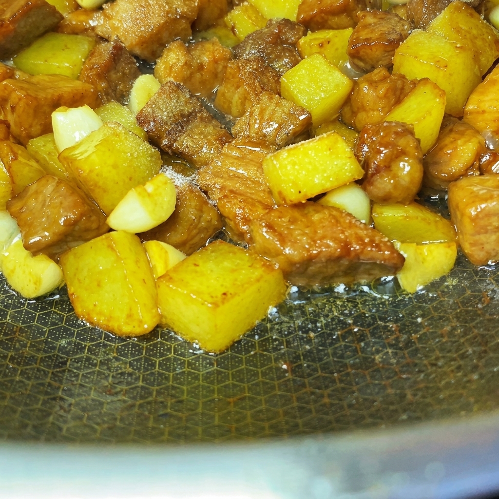 Spices and sesame seeds evenly sprinkled over the pan-fried pork and potato cubes.