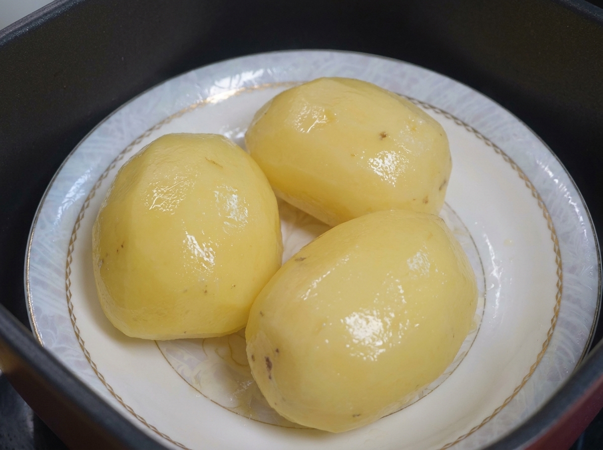 Steamed potatoes on a plate ready to be coated with oil.
