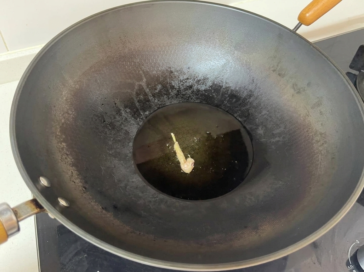 A single coated chicken piece frying in the center of a large wok with hot oil.