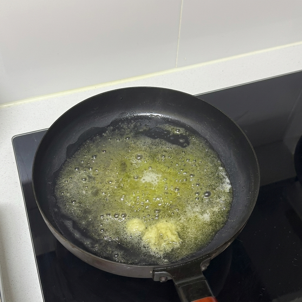 Minced garlic cooking in melted butter in a frying pan.
