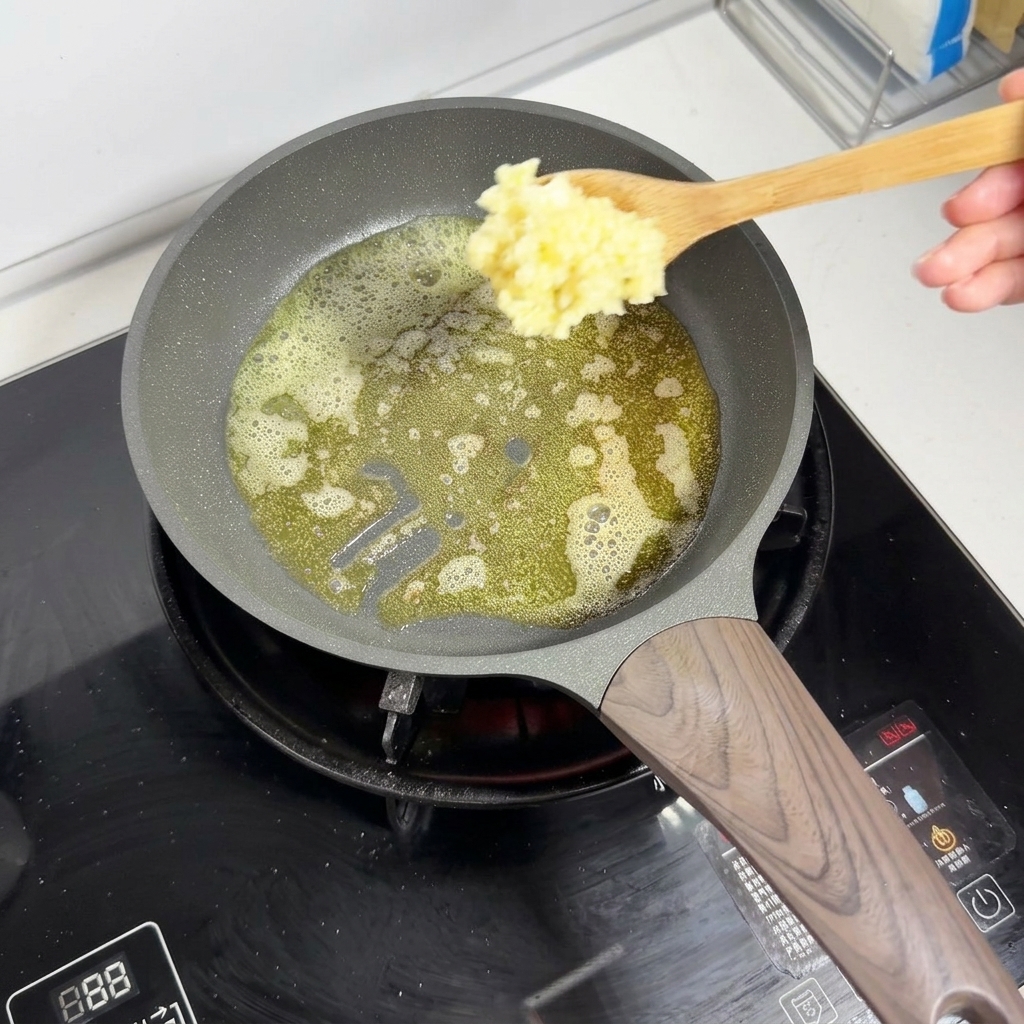 A wooden spoon adding minced garlic into melted foaming butter in a pan.