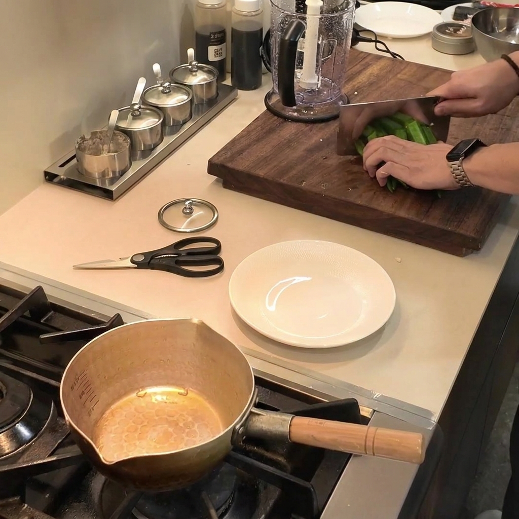 Chopping fresh green okra into small pieces on a wooden cutting board using a cleaver.