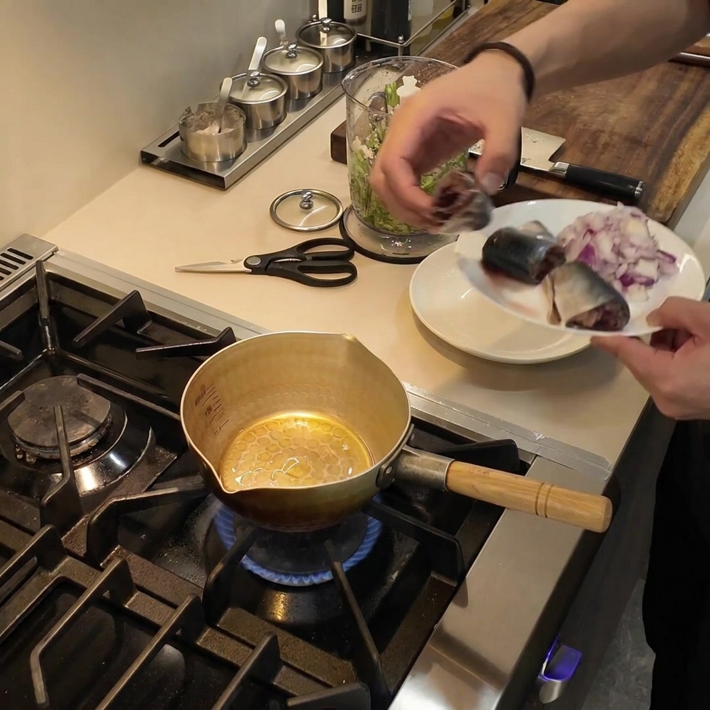 A small golden pot sitting on a gas burner with cooking oil shimmering inside.