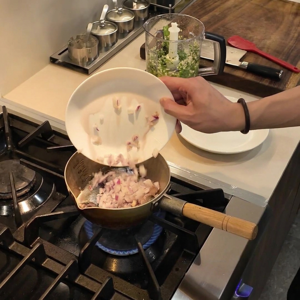 Diced red onions sliding from a white plate into a pot of hot oil on the stove.