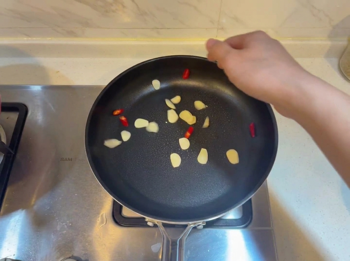 Garlic slices and red chili pieces sizzling in a hot oiled pan.