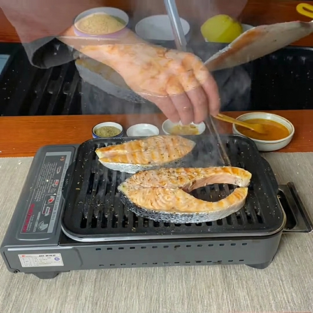 Salmon steaks being flipped over with a spatula on a hot grill pan.