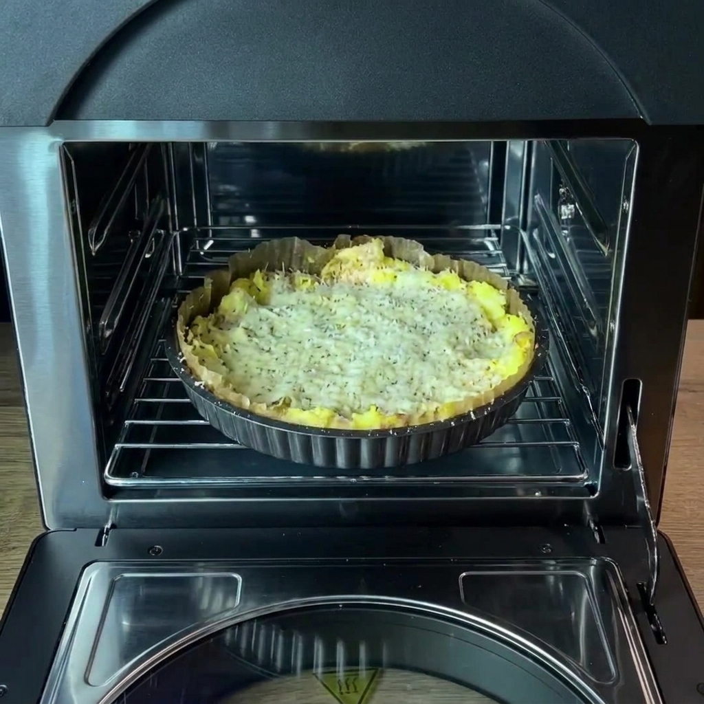 The baking pan with the seasoned potato crust placed on the oven rack inside the oven.