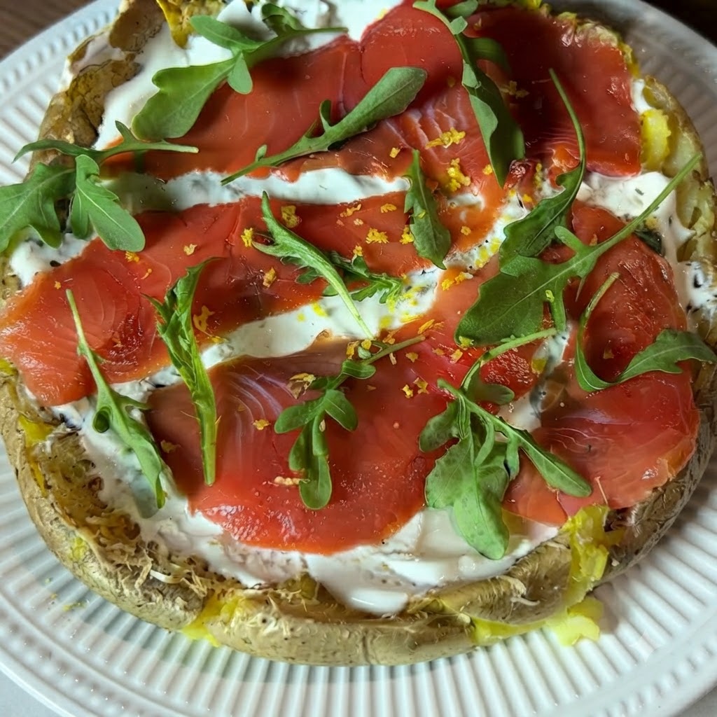 A close-up view of freshly grated yellow lemon zest being sprinkled over the topped potato pizza.