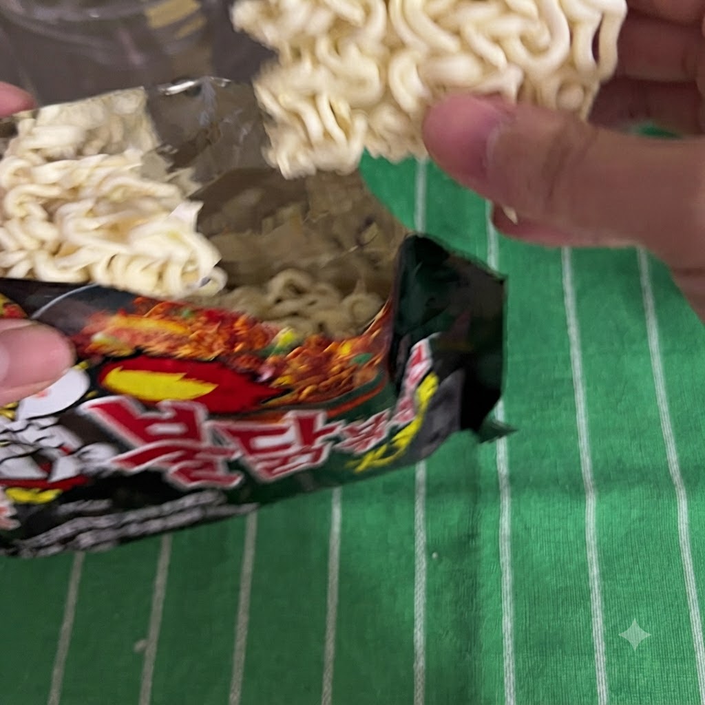 Instant noodles being taken out of a black packaging bag.