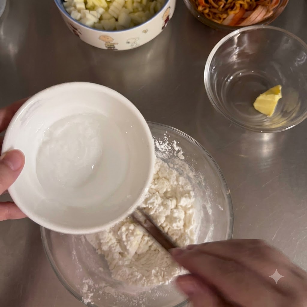Hot water being poured from a small white bowl into a glass bowl filled with flour mixture.