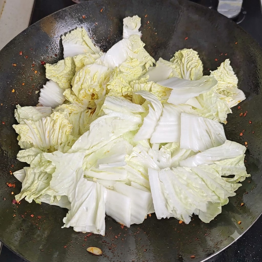 Vinegar being poured along the heated perimeter of the wok, reacting with the hot surface.