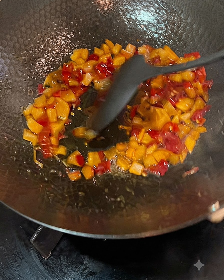 Broth being poured from a pitcher into a wok with sautéed pickled radishes and chilies.
