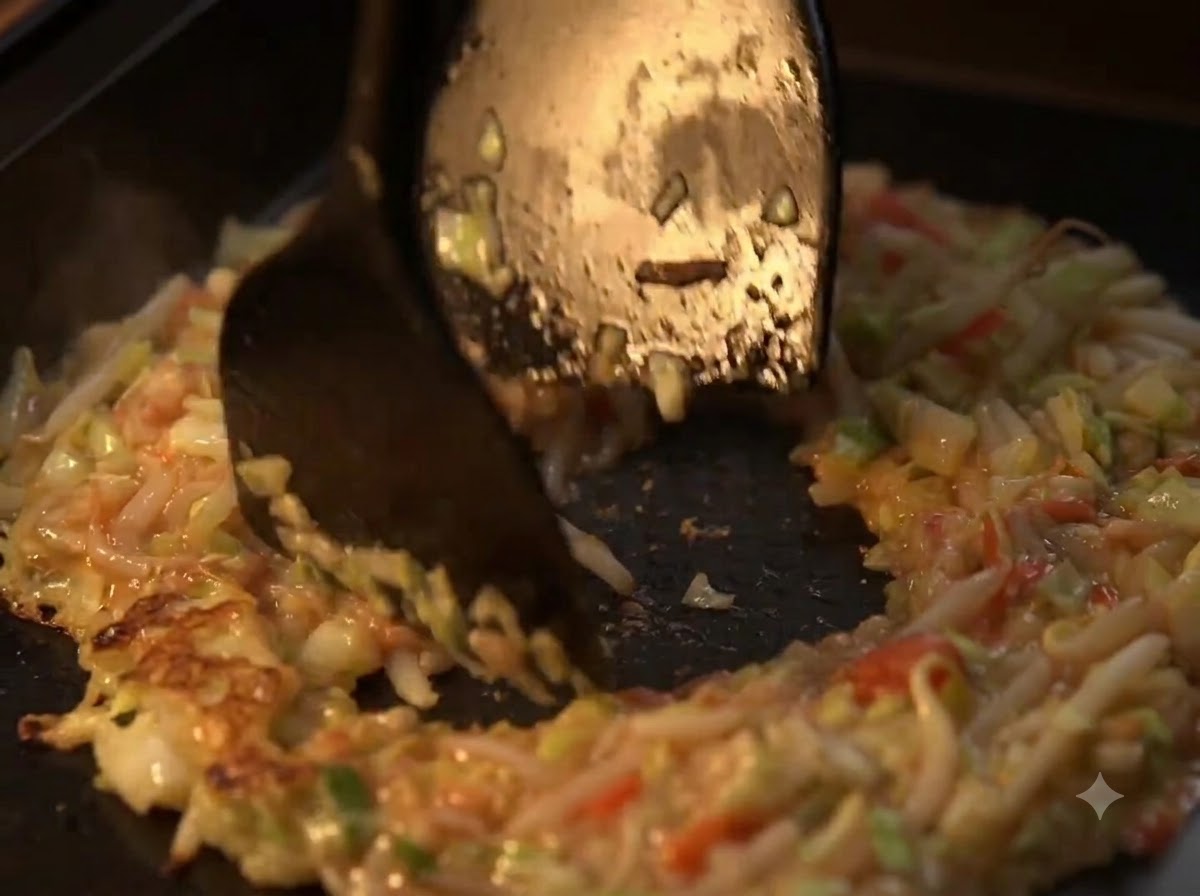 Spatulas shaping the stir-fried vegetable mixture into a ring with a hollow center on a hot plate.