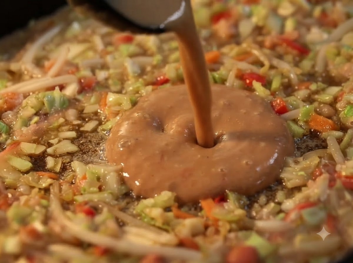 Liquid batter being poured into the hollow center of a vegetable ring on a hot griddle.