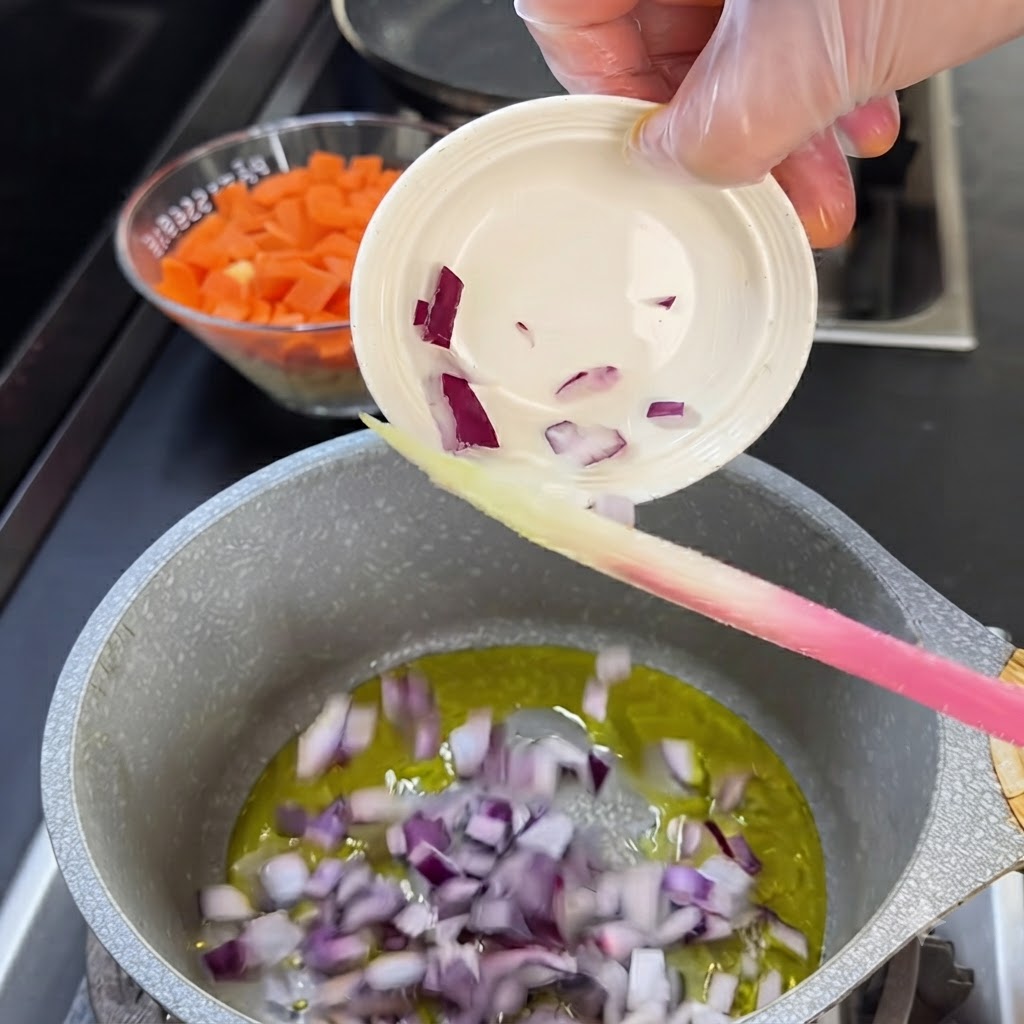 Red onion pieces being poured from a small white bowl into a pot of hot oil.