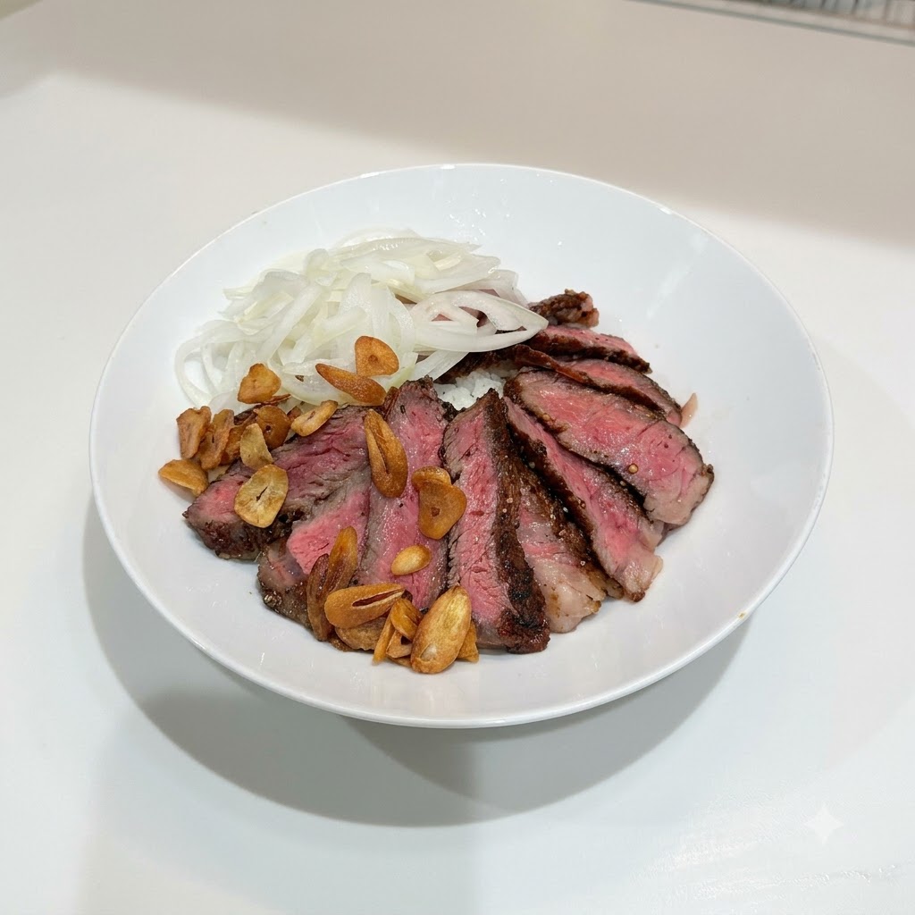 A white bowl containing sliced steak, sliced onions, and a scattering of golden-brown crispy garlic chips on top of rice.