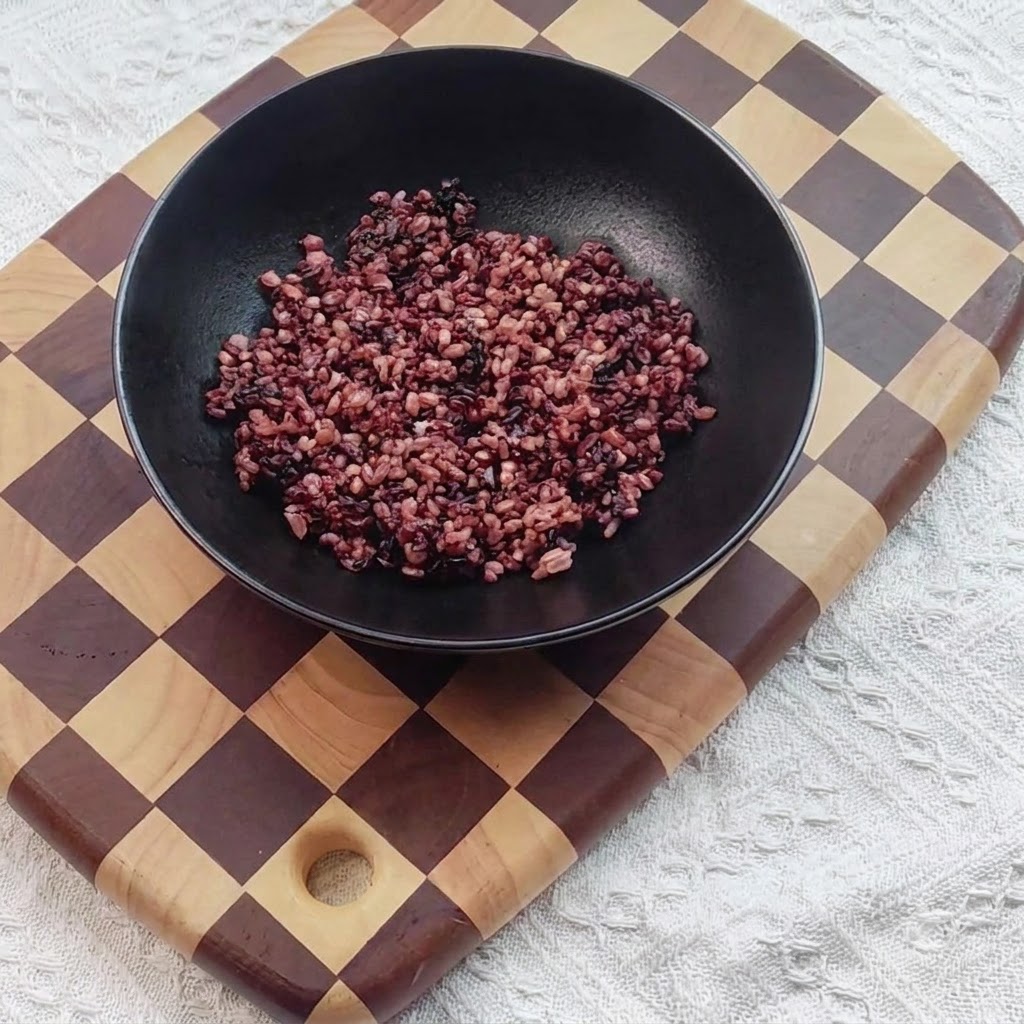 Cooked black rice placed inside a black serving bowl.