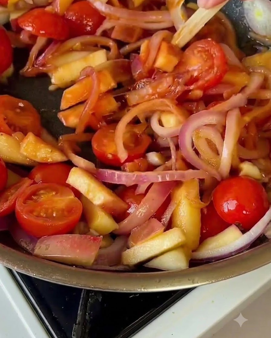 Napa cabbage mixed into the pan with tomatoes and onions.