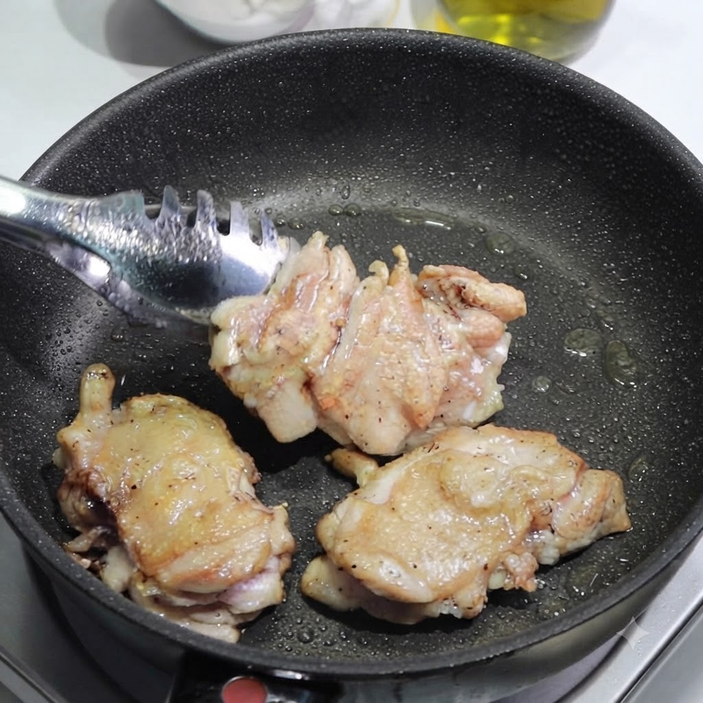 Tongs placing browned chicken thighs out of a pan onto a cutting board to be sliced.