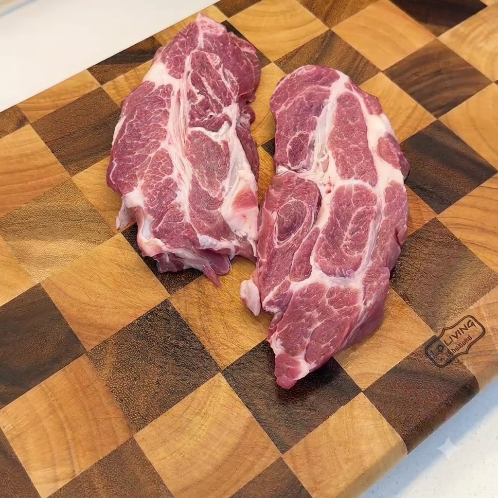 Raw pork shoulder cuts being pounded with a metal meat mallet on a wooden cutting board.