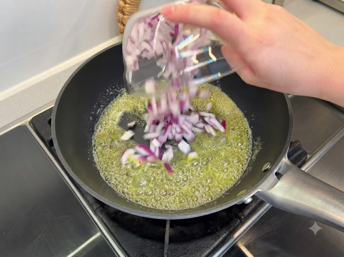 Diced purple onions being sautéed in melted butter inside a black frying pan.
