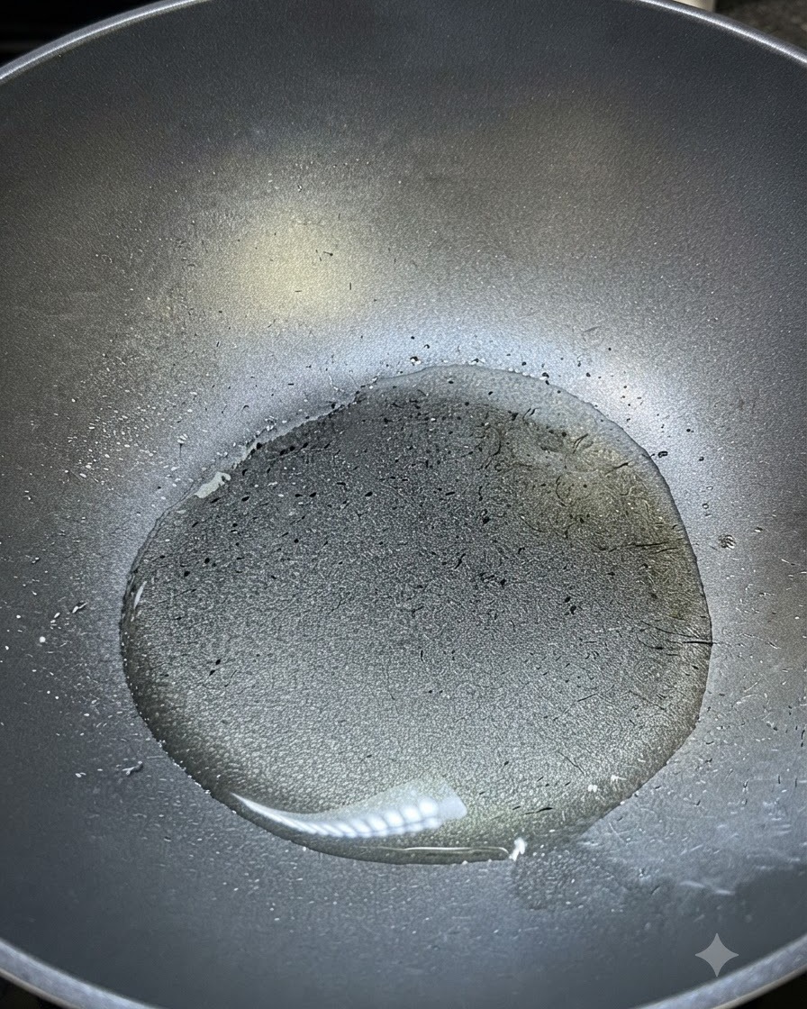 Hot cooking oil shimmering inside a dark wok ready for seasoning.