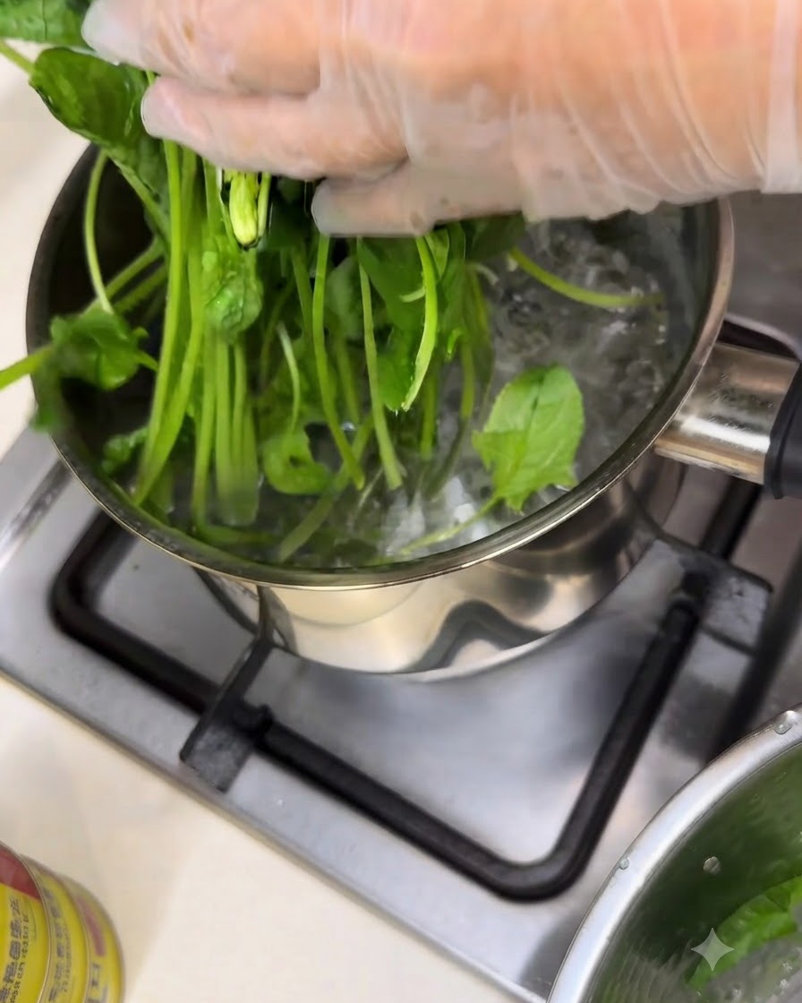 Fresh spinach being blanched in a pot of boiling water on a stove burner.