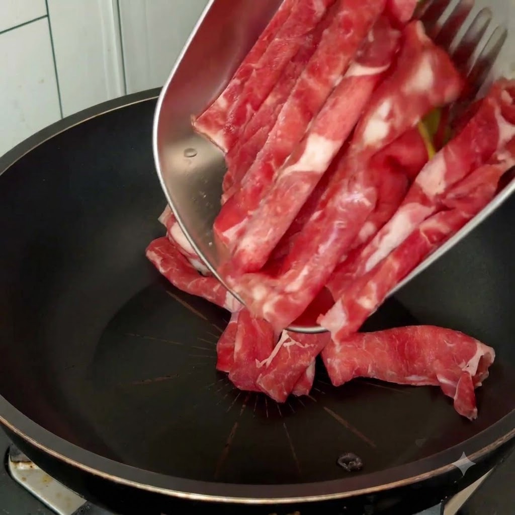 Raw beef slices being poured into a black pan from a metal tray with cooking utensils.
