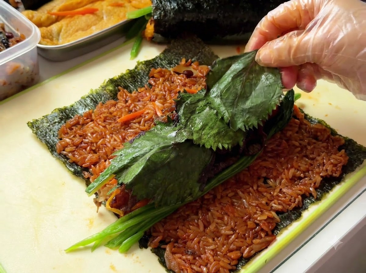 Perilla leaves being laid across the top of the filling ingredients.