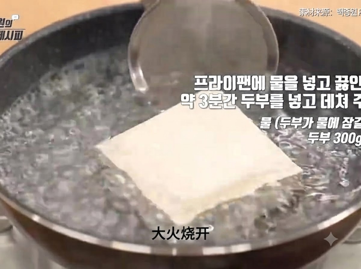 A block of firm tofu submerged in a pot of vigorously boiling water during the blanching process.