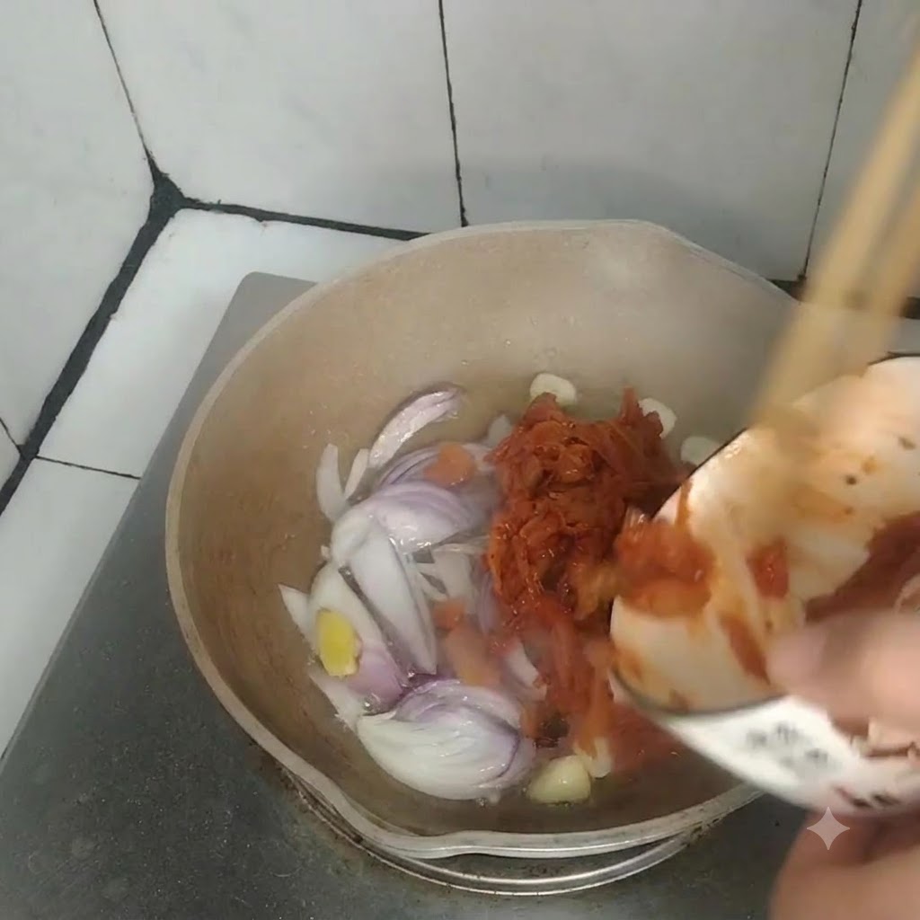 Kimchi being poured from a small bowl into a pan containing sautéed onions, garlic, and ginger.