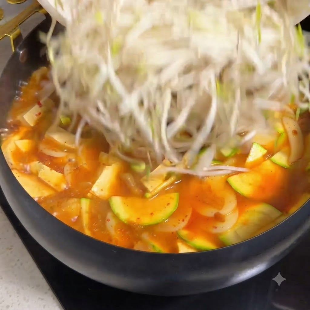 Shredded mozzarella cheese being sprinkled over the tomato beef stew around the rice dome.