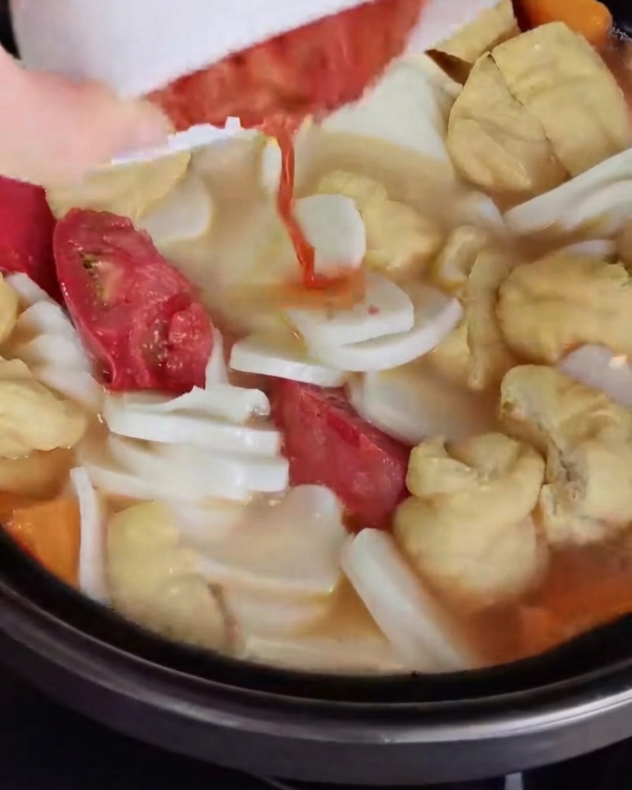 Chopped kimchi being poured and mixed into the soup broth.