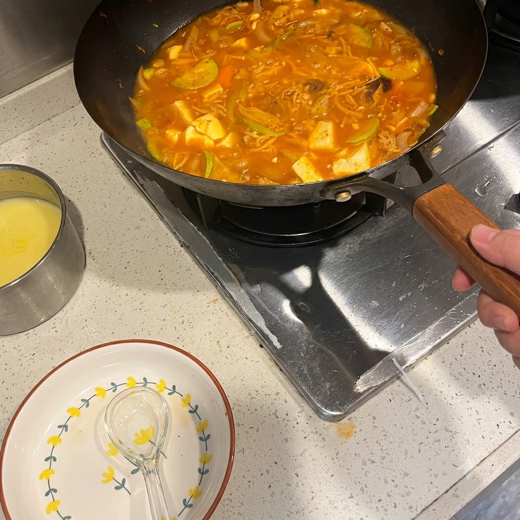 Korean chili paste being mixed into a simmering pot of spicy soup with vegetables and meat.