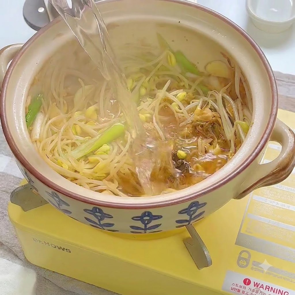 Water being poured into the ceramic pot over the sautéed vegetable mixture.