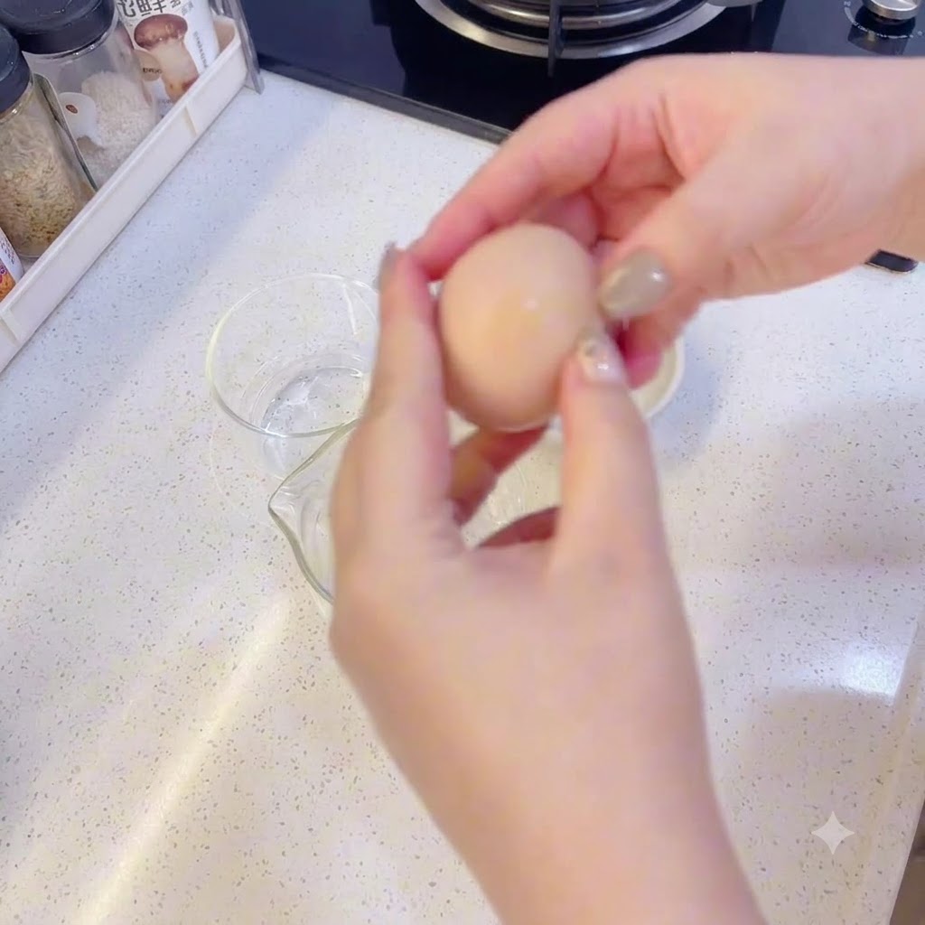Hands carefully separating an egg yolk from the egg white over clear glass bowls.
