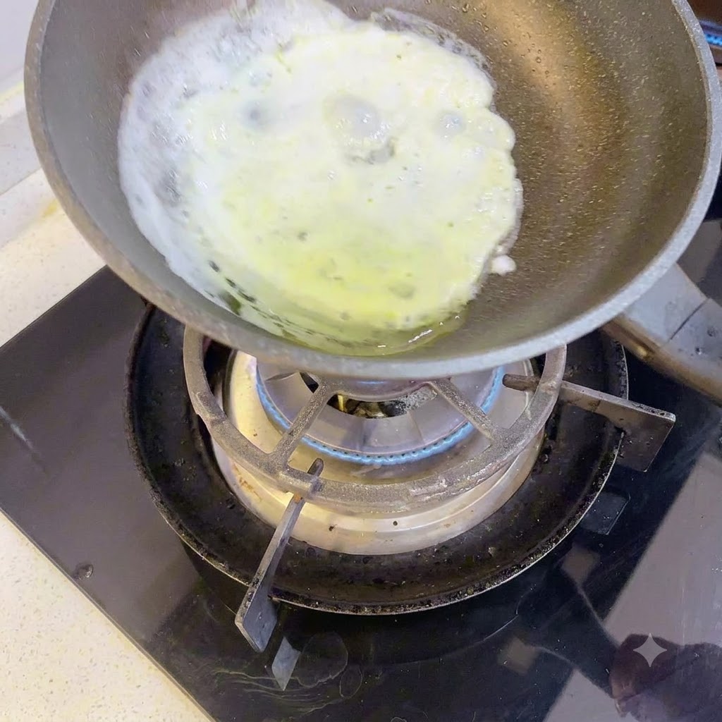 A thin layer of egg white cooking in a small skillet over a gas burner.