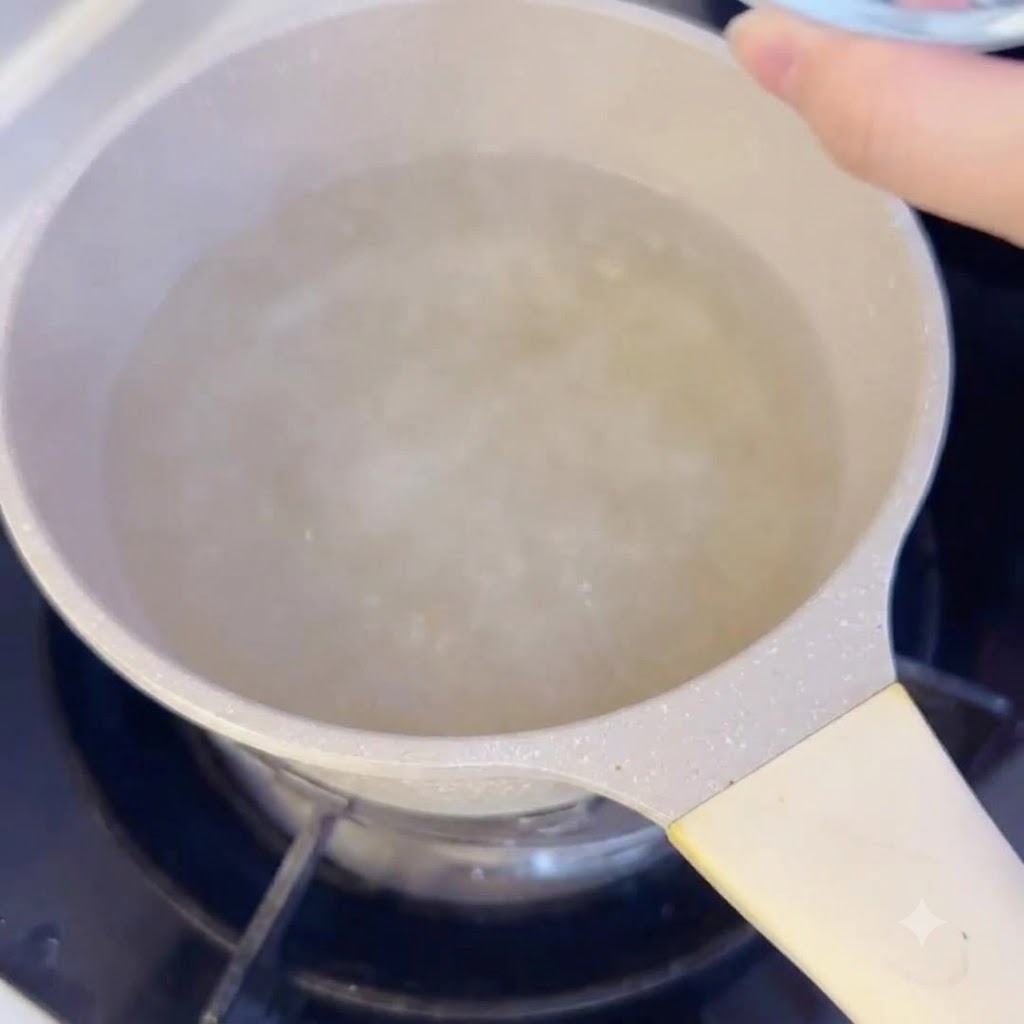 Sliced rice cakes being dropped into a pot of boiling broth on the stove.