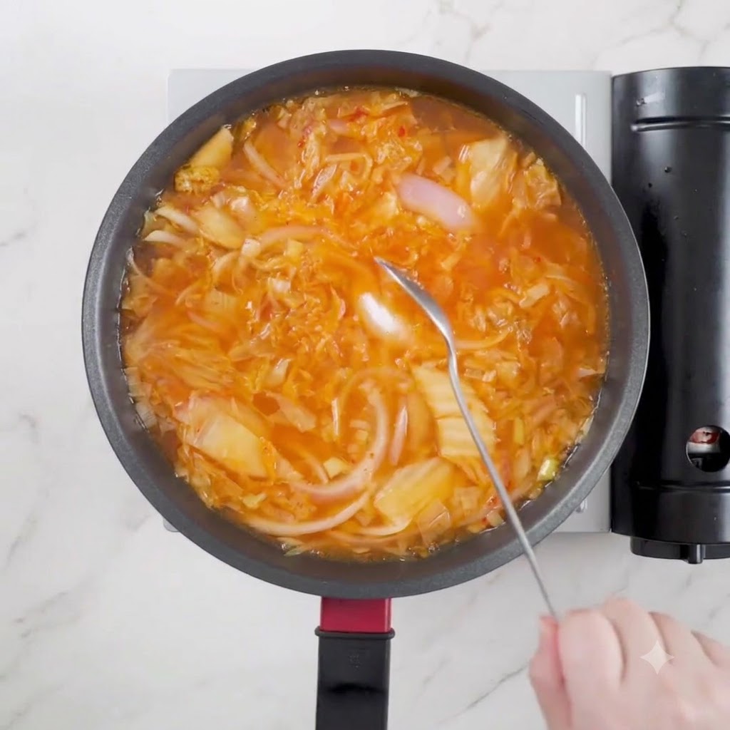 One spoon of light soy sauce being poured into the simmering soup pot.