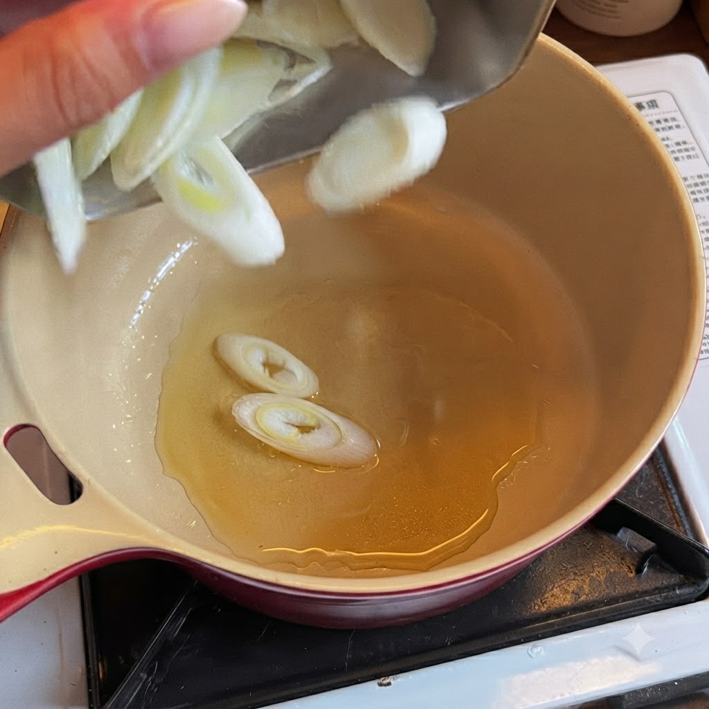 Sliced green onions dropping into a pot filled with cooking oil.