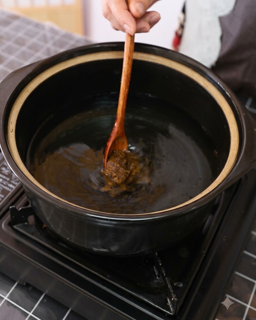 Brown soybean paste being stirred into a pot of water with a wooden spoon.